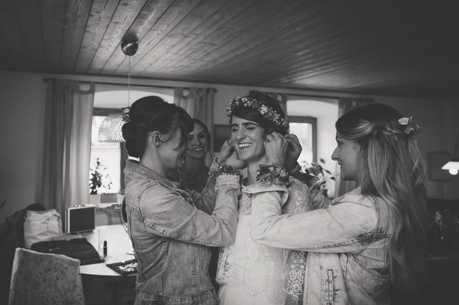 bride with flower crown getting ready on rustic farm with bridesmaids in denim jackets
