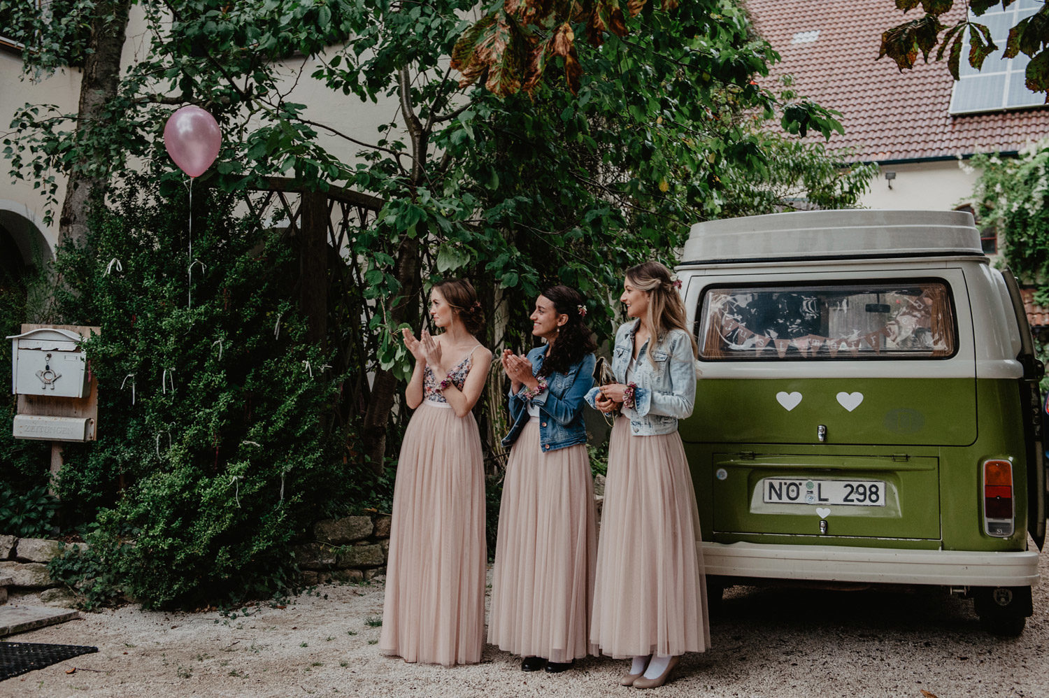 boho bridesmaids wearing denim jackets and pastel tulle dresses clapping during first look