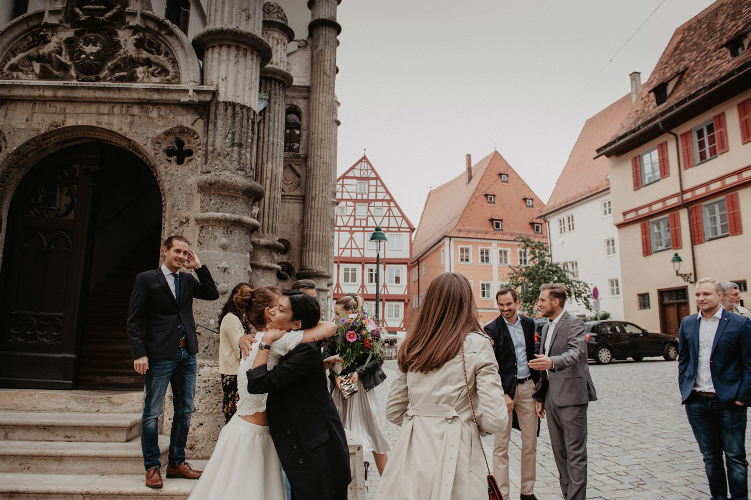 bride hugging guest in cobbled town square outside medieval town hall