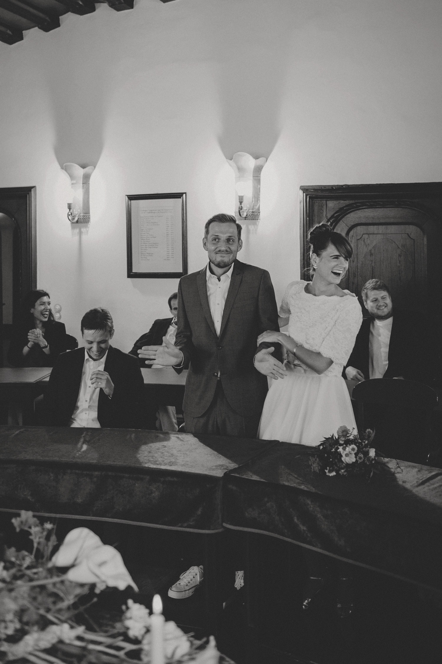 groom shrugging in jest and bride laughing during bohemian registry office ceremony in noerdlingen germany