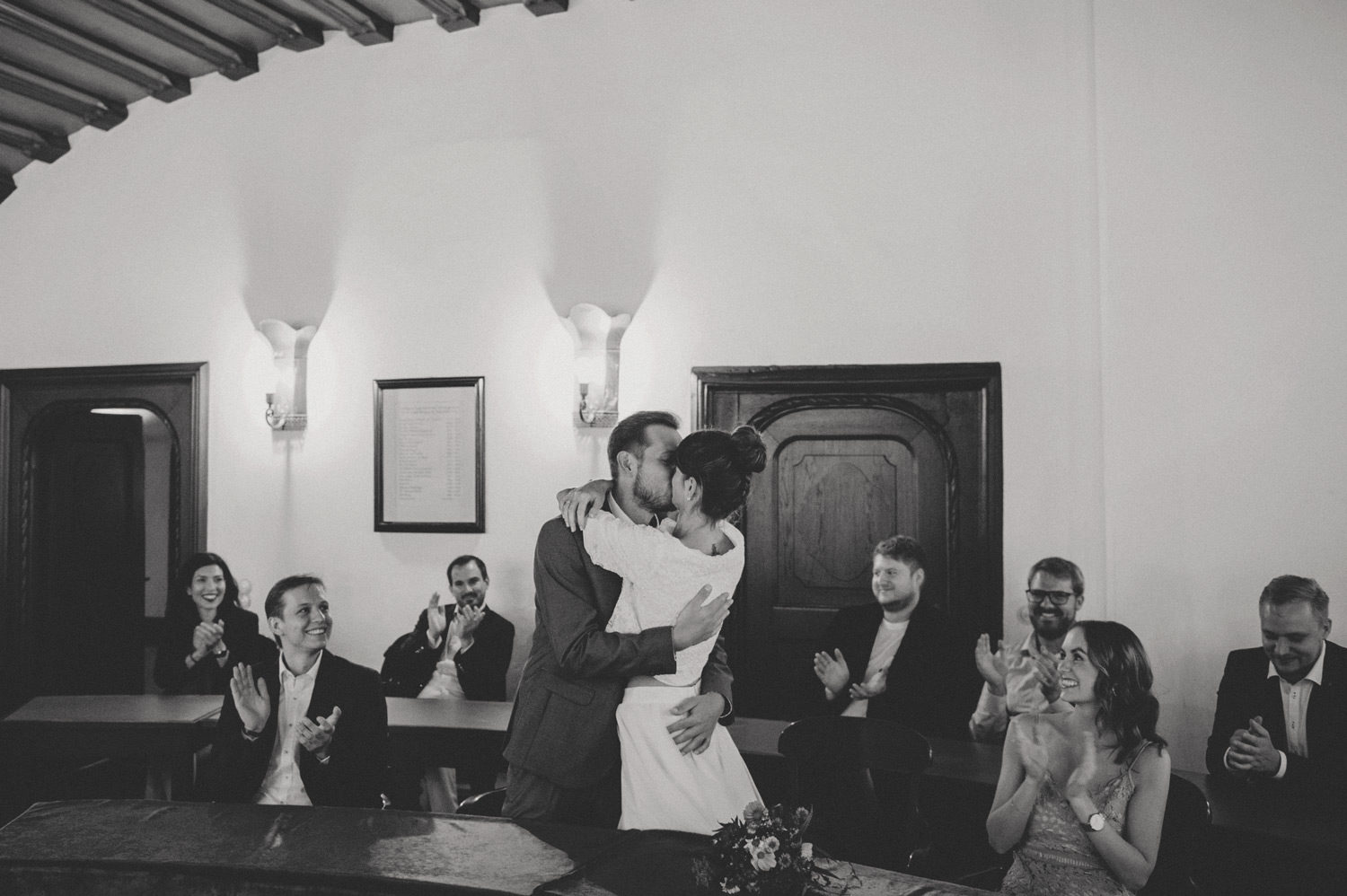 bride and groom kissing with friends applauding during registry office ceremony at bohemian wedding in bavaria