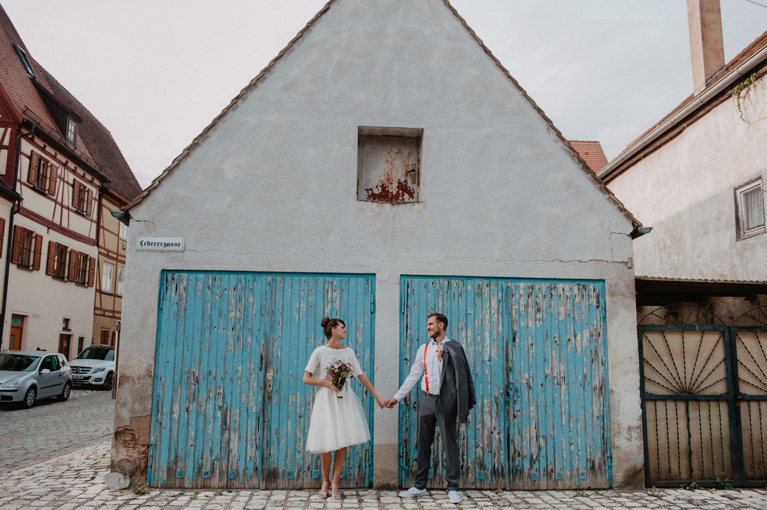 boho bride and groom in front of blue garage door with peeling paint in bavaria