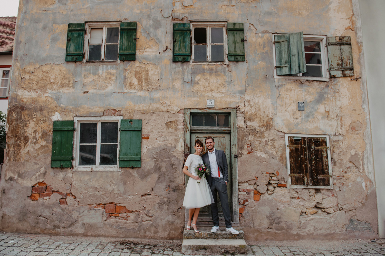 boho wedding couple in front of italian sandstone house with crumbling facade noerdlingen