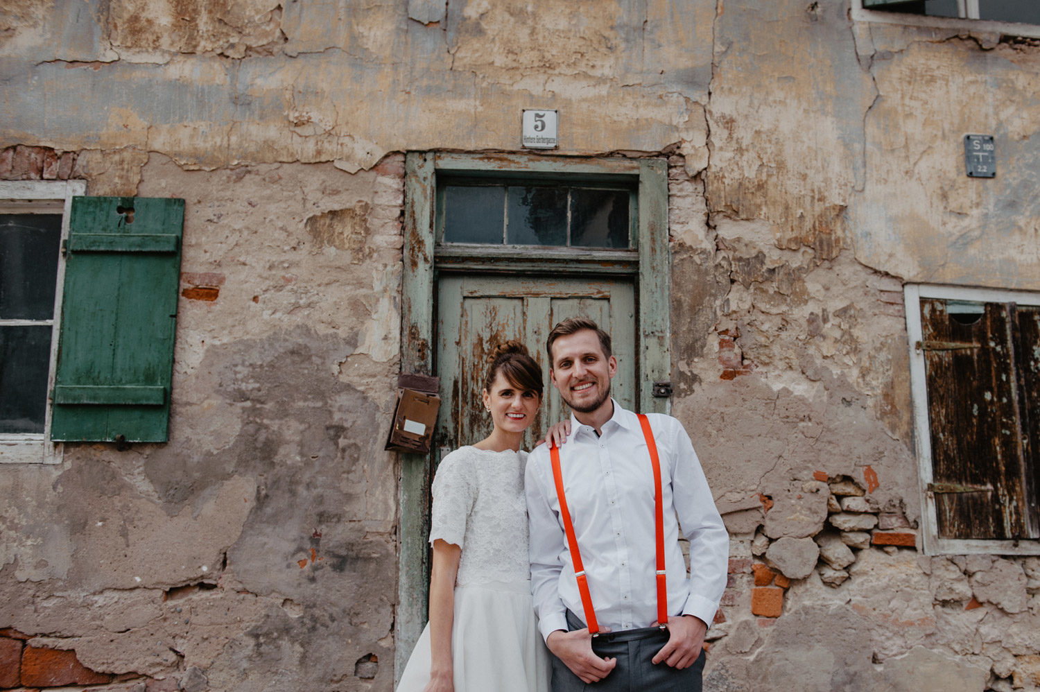 smiling boho wedding couple in front of italian sandstone house with crumbling facade noerdlingen