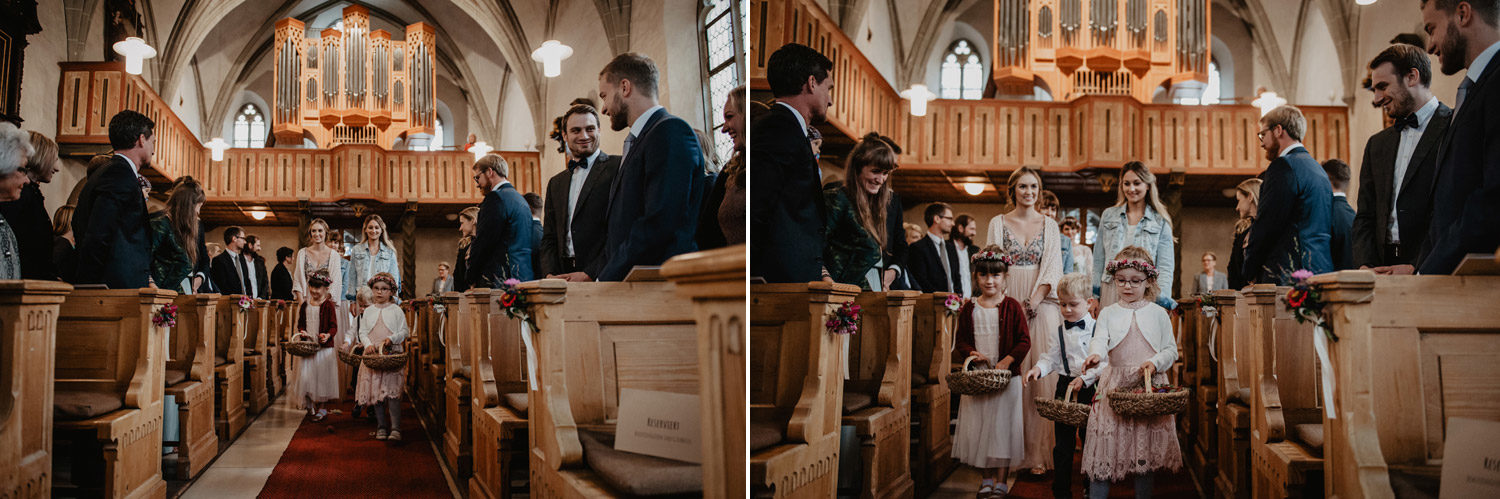 flowergirls and boho bridesmaids walking down aisle in wood panelled church noerdlingen germany