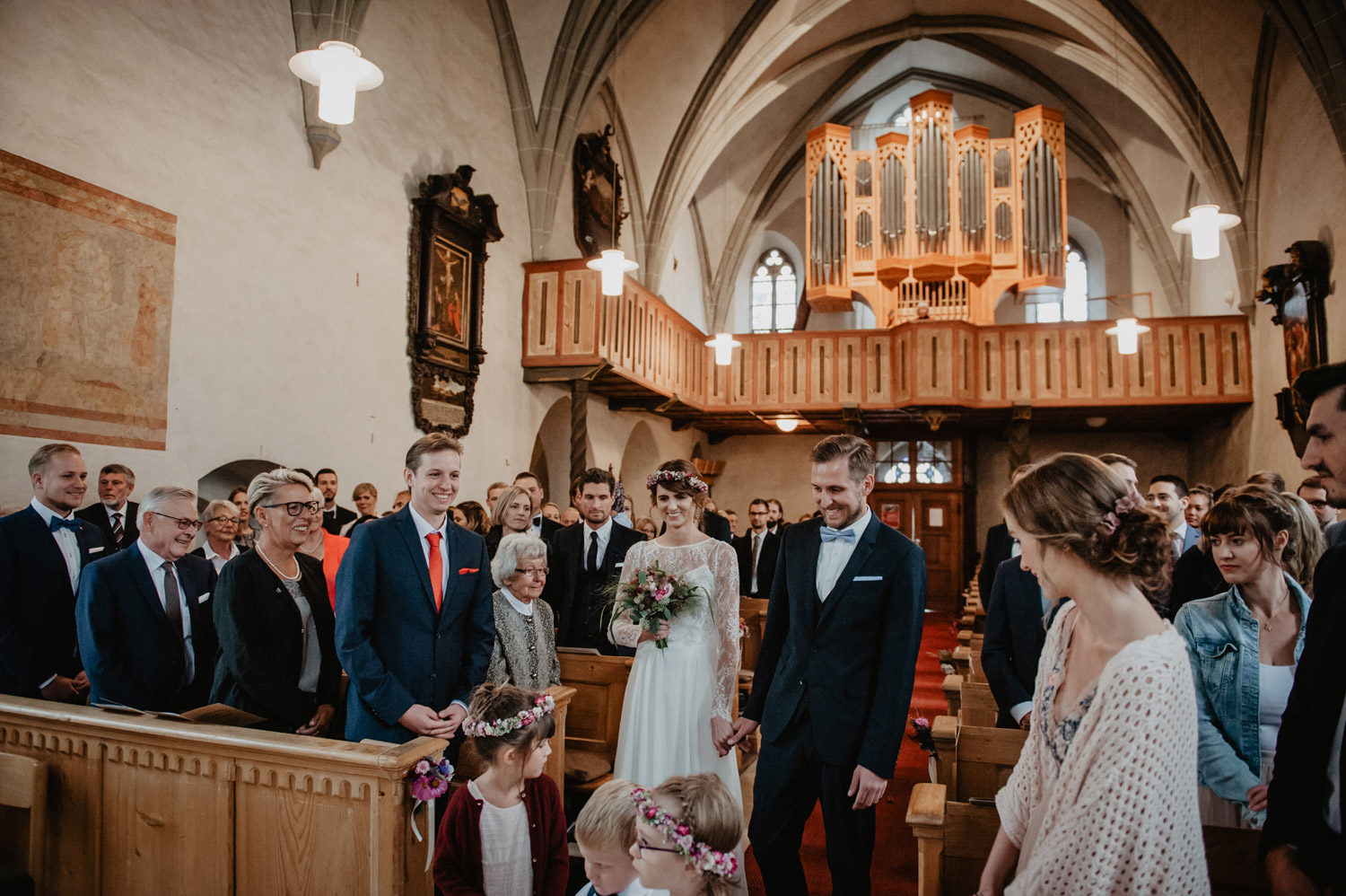 bride and groom boho wedding walking down aisle in wood panelled church noerdlingen