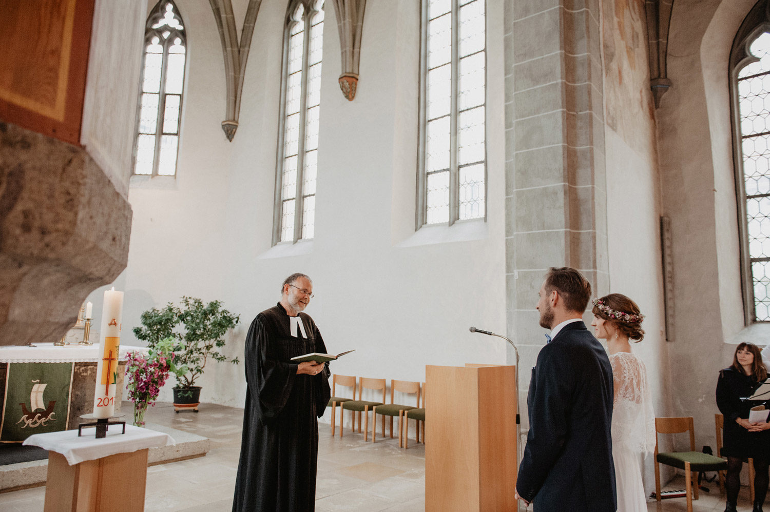 pastor in scandinavian church speaking to bride and groom during boho folk inspired ceremony 