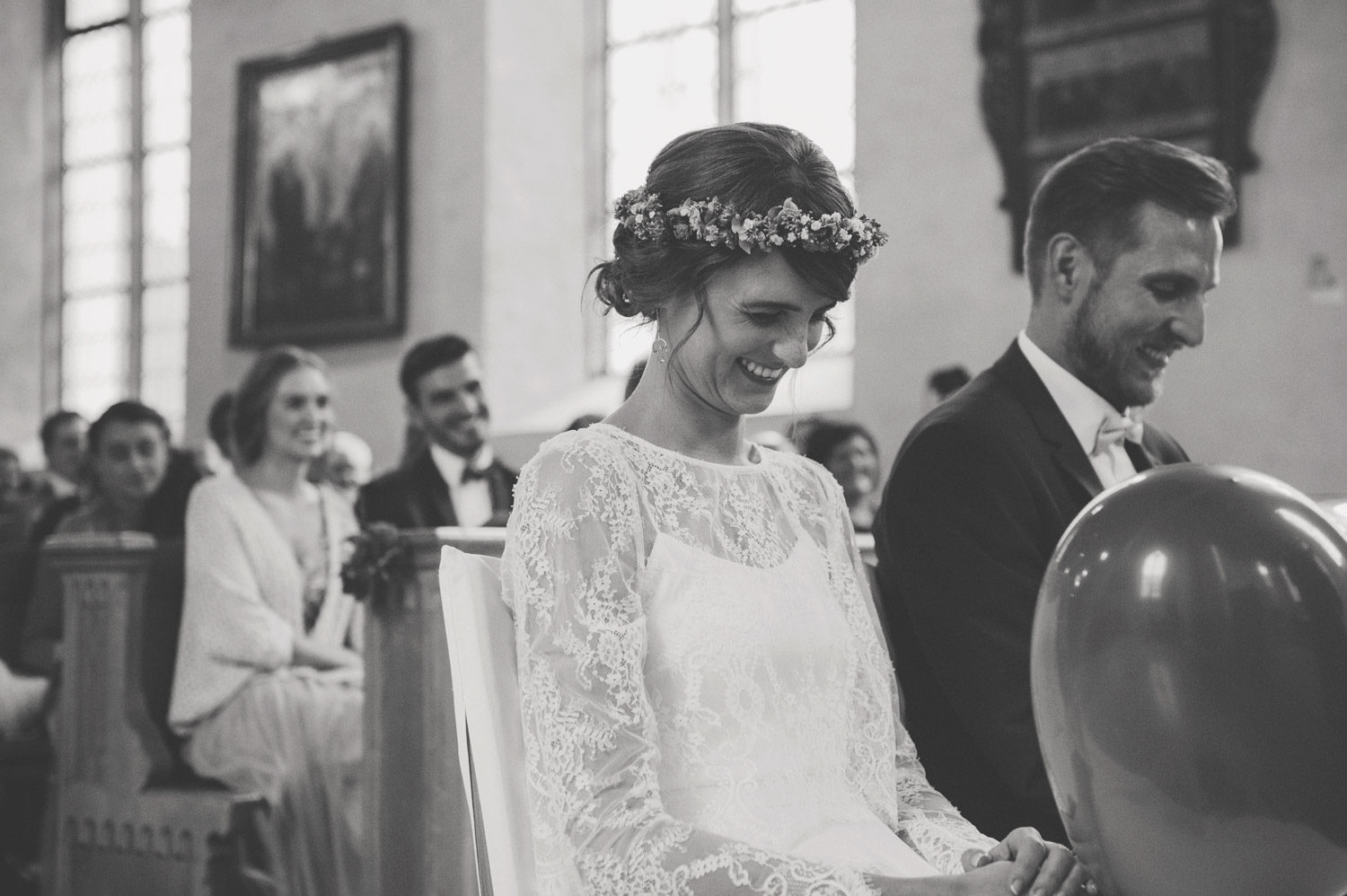 couple blowing up red heart balloons during boho church ceremony 