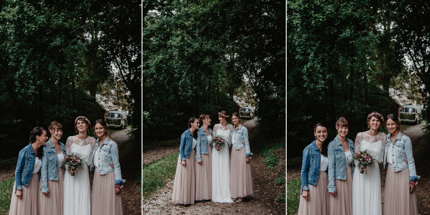 boho bride with flowercrown and bridesmaids in denim jackets pastel tulle skirts with balloons posing at tipi wedding in forest