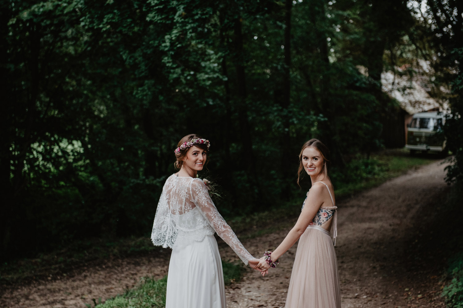 boho bride with flowercrown holding hands with bridesmaid at tipi wedding in forest