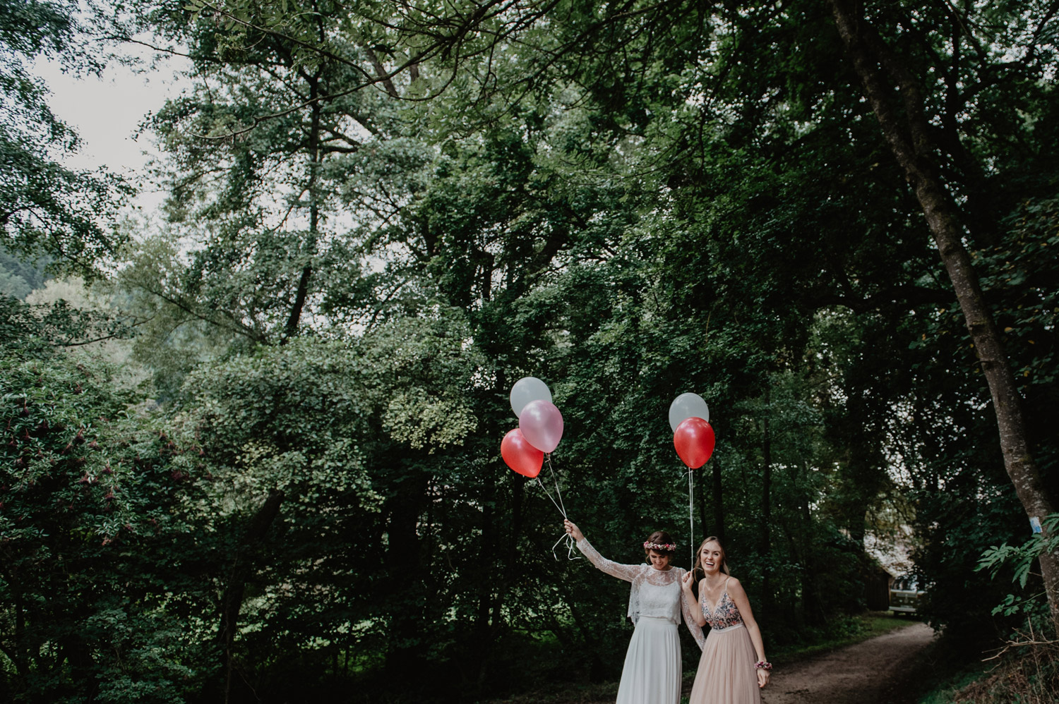 boho bride with flowercrown and bridesmaid with balloons at tipi wedding in forest