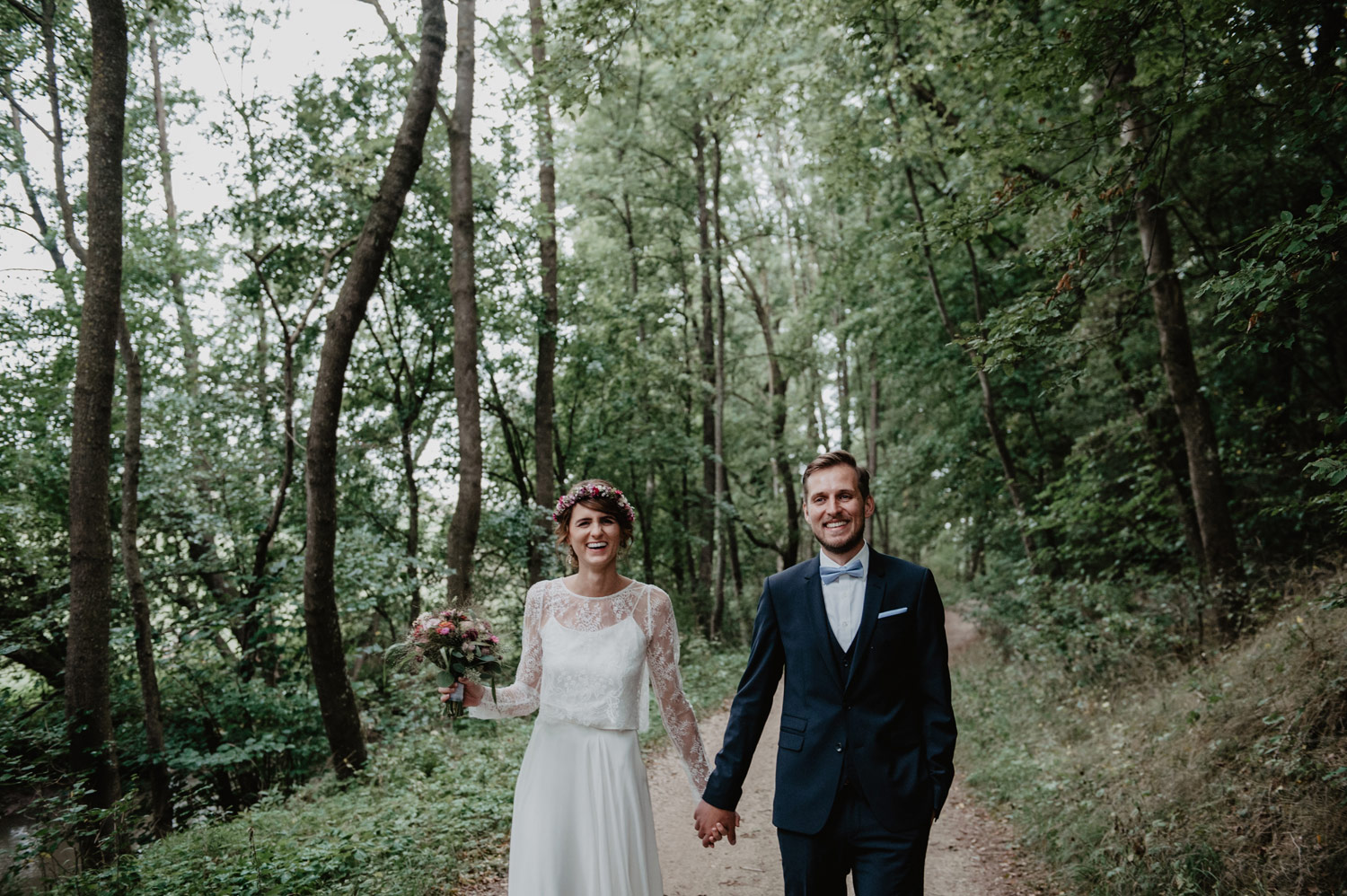 boho bride in elfenkleid wedding dress and groom walking in forest