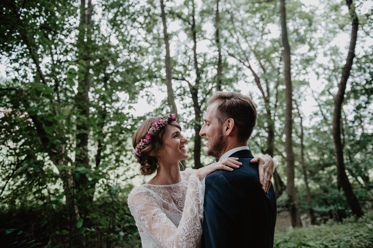 boho bride in elfenkleid wedding dress and groom kissing in rain in forest