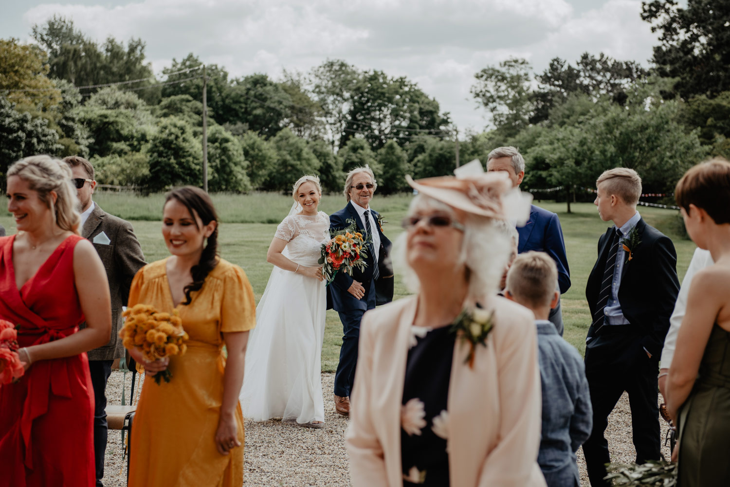 abbey hall eye suffolk wedding smiling bride walking down the aisle carrying a pink peony bouquet by anne schwarz photography