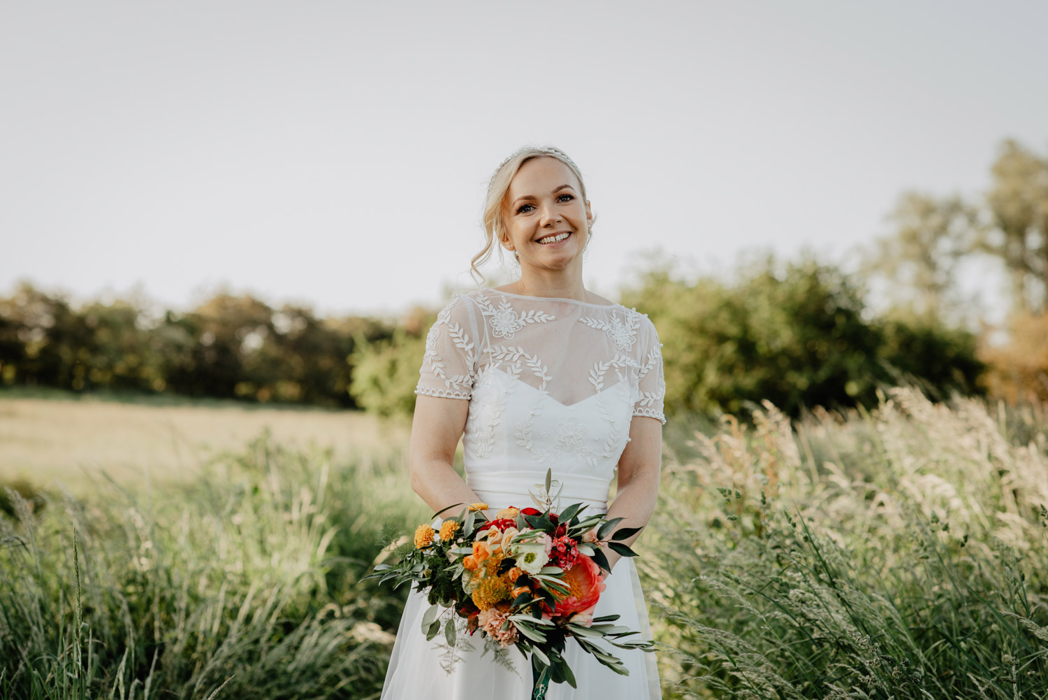 abbey hall eye suffolk wedding smiling bride walking down the aisle carrying a pink peony bouquet by anne schwarz photography